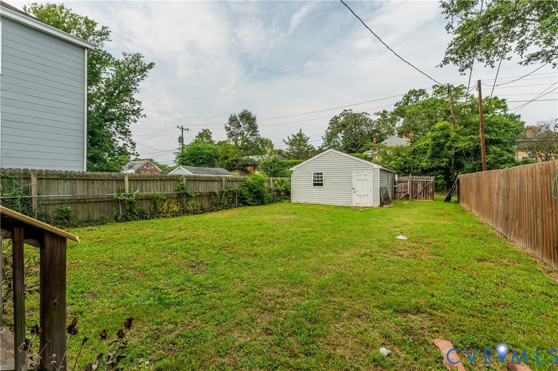 Spacious lawn with a detached shed, wood privacy fencing, and mature perimeter trees