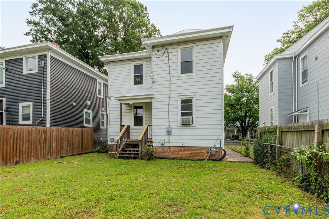Expansive grassy yard with wood fencing and rear porch access