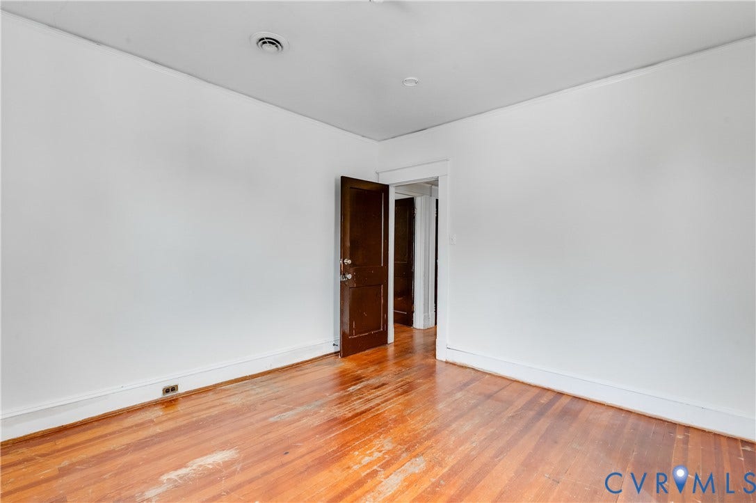 Hardwood flooring, painted walls, white trim, and a dark wood-finish door