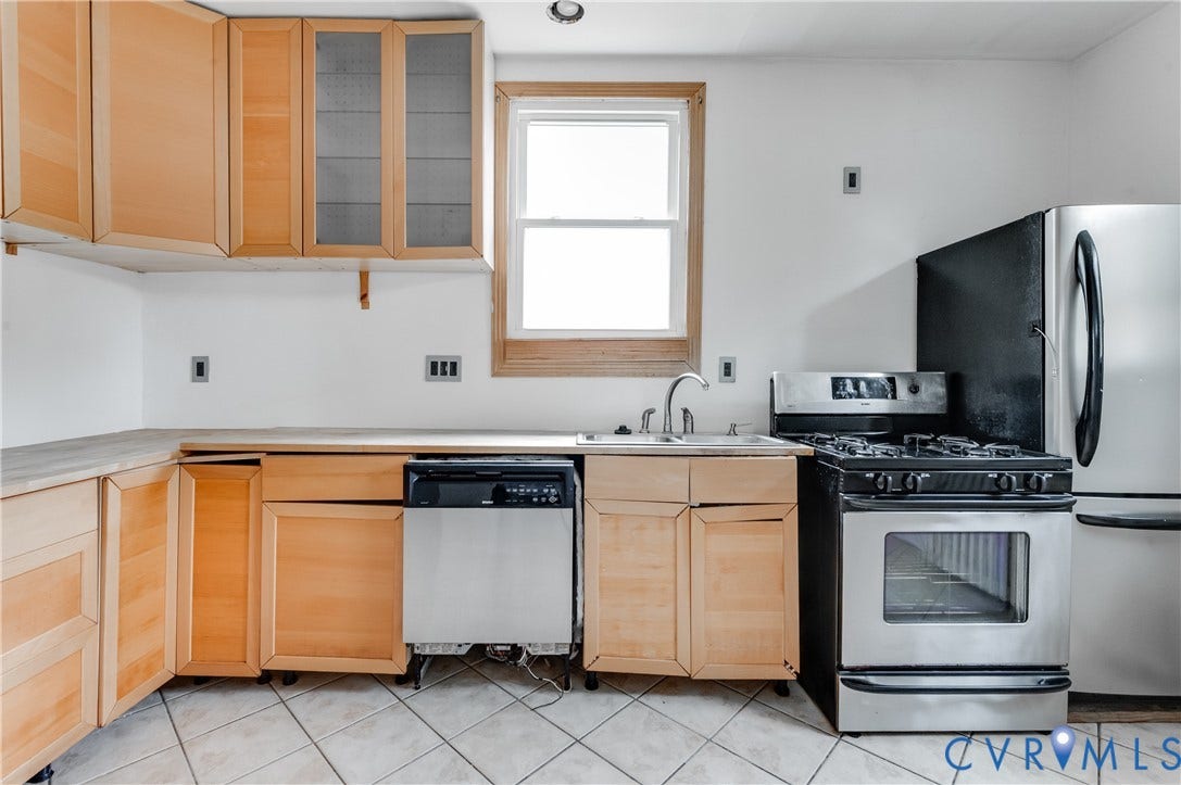 Light wood-finish cabinetry with glass upper doors, white appliance package, stainless steel gas range, and a single basin sink