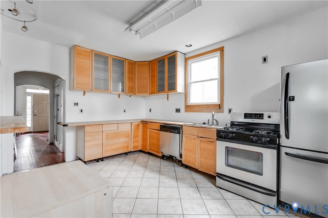 Kitchen featuring wood-finish cabinetry, tile flooring, stainless steel appliances, and an arched entryway