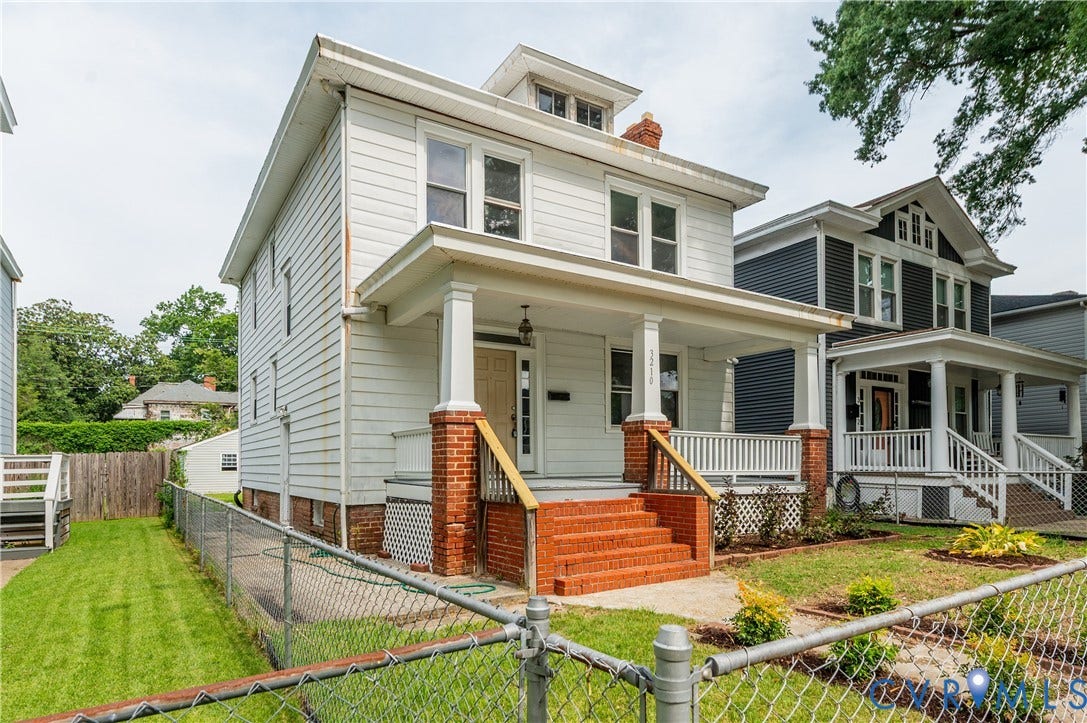 Two-story white siding exterior with a covered front porch, brick foundation, and dormer window