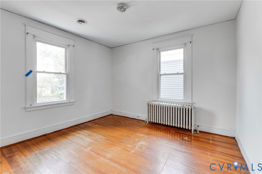 Hardwood-style flooring with white baseboards, white walls, and two windows with white trim
