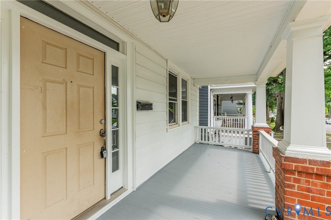 Expansive covered front porch with painted wood flooring and white railings