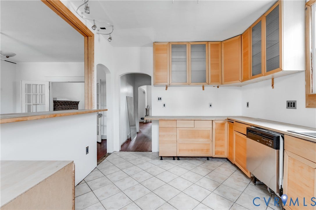Kitchen featuring light wood-finish cabinetry, stainless steel dishwasher, white countertop, and tiled flooring