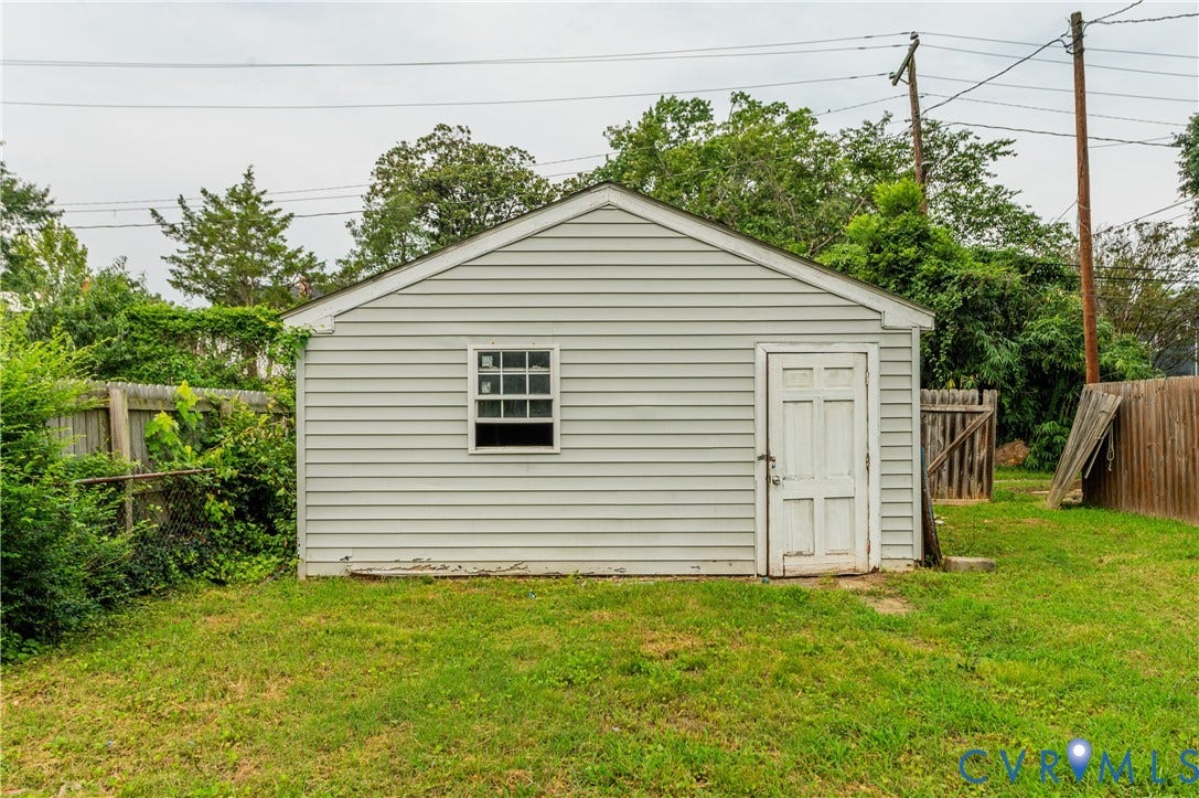 Detached utility building with horizontal siding and a side-hinged entry door