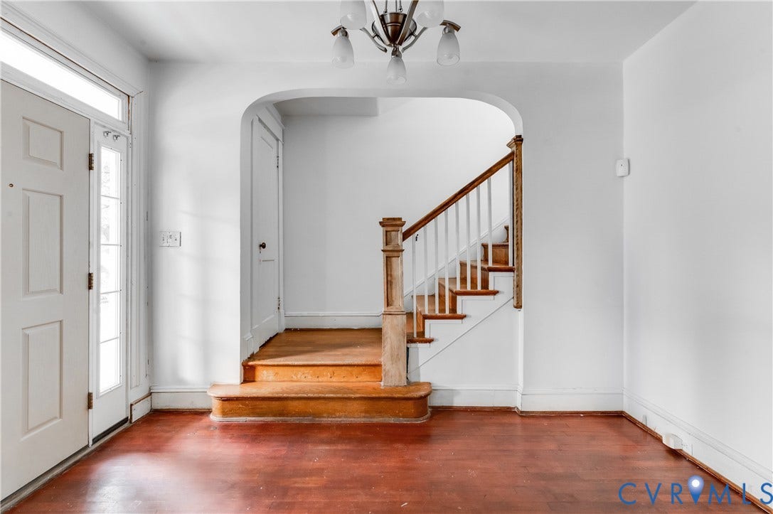 Entryway featuring a paneled door with sidelight, wood-finish flooring, and a staircase with wood newel posts and railings
