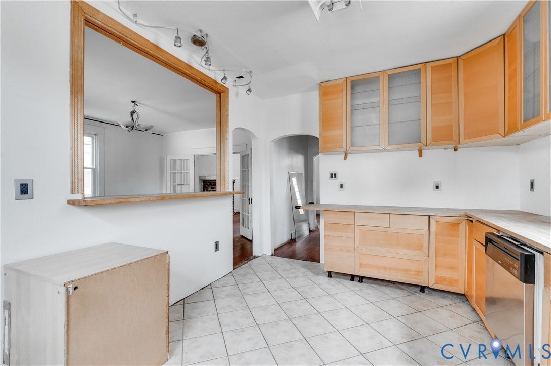 Tile flooring, wood-finish cabinetry, and a pass-through window with wood trim