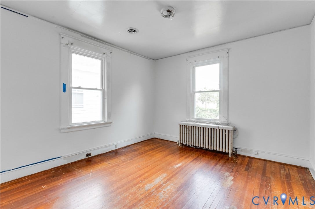 Hardwood flooring, painted white walls, two double-hung windows, and a classic radiator