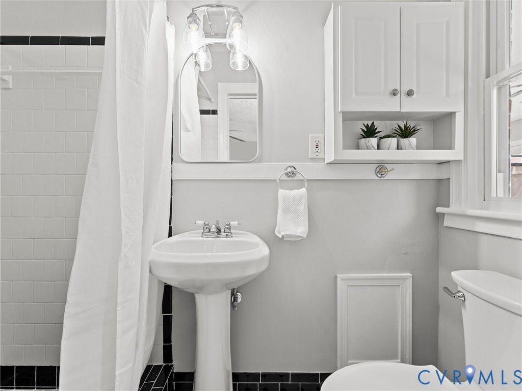 En suite bath with tile flooring, tile shower, new fixtures and finishes, fresh paint, and new toilet