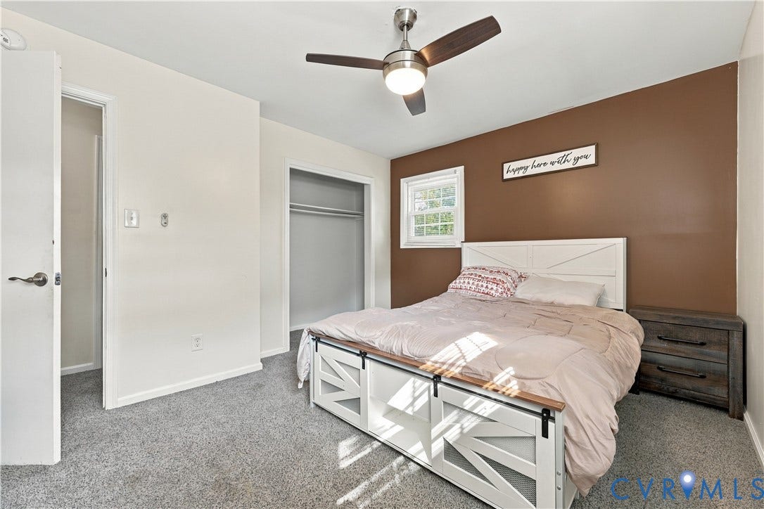 Carpeted bedroom with a window and a ceiling fan with integrated lighting