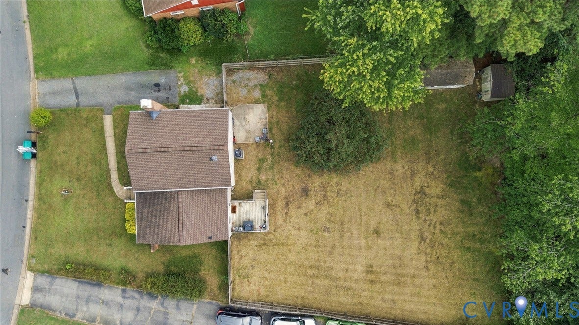 Expansive property with a brown shingle roof, paved driveway, concrete patio, and a storage shed