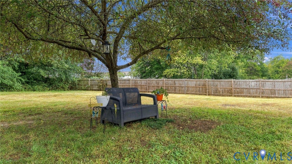 Expansive backyard featuring a mature shade tree and wood privacy fencing
