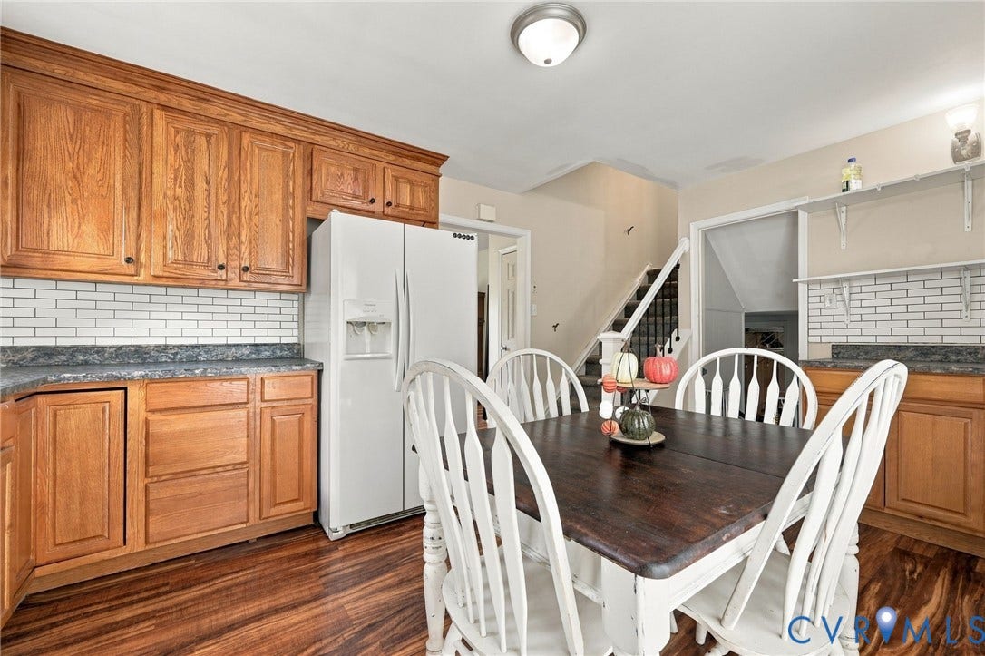 Wood-finish flooring, wood cabinetry, subway tile backsplash, built-in shelving, and a dual-door refrigerator