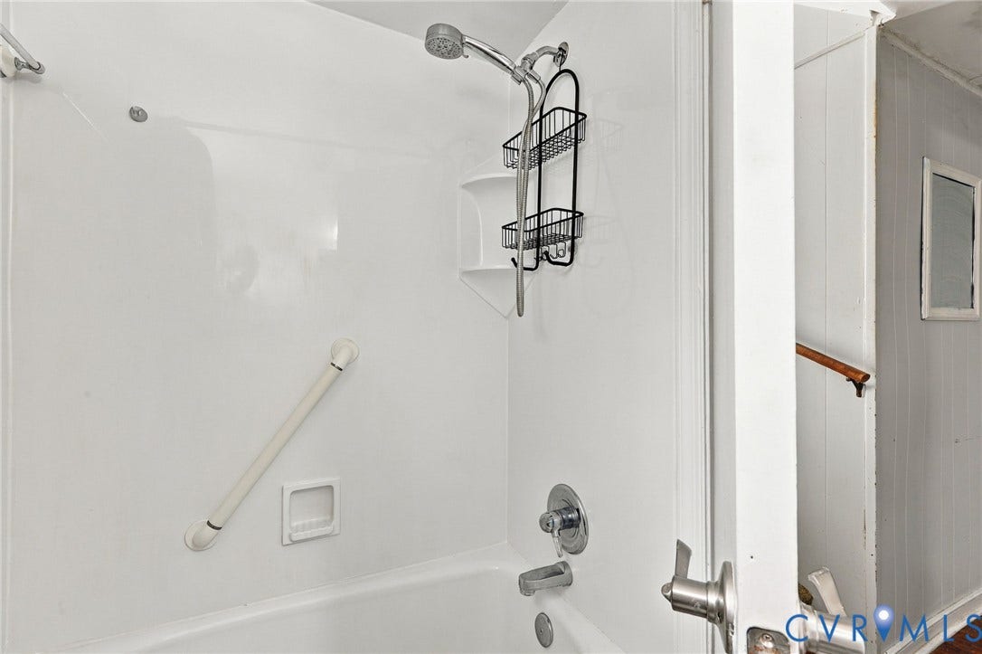 White tub and shower combination with chrome fixtures and an integrated soap dish