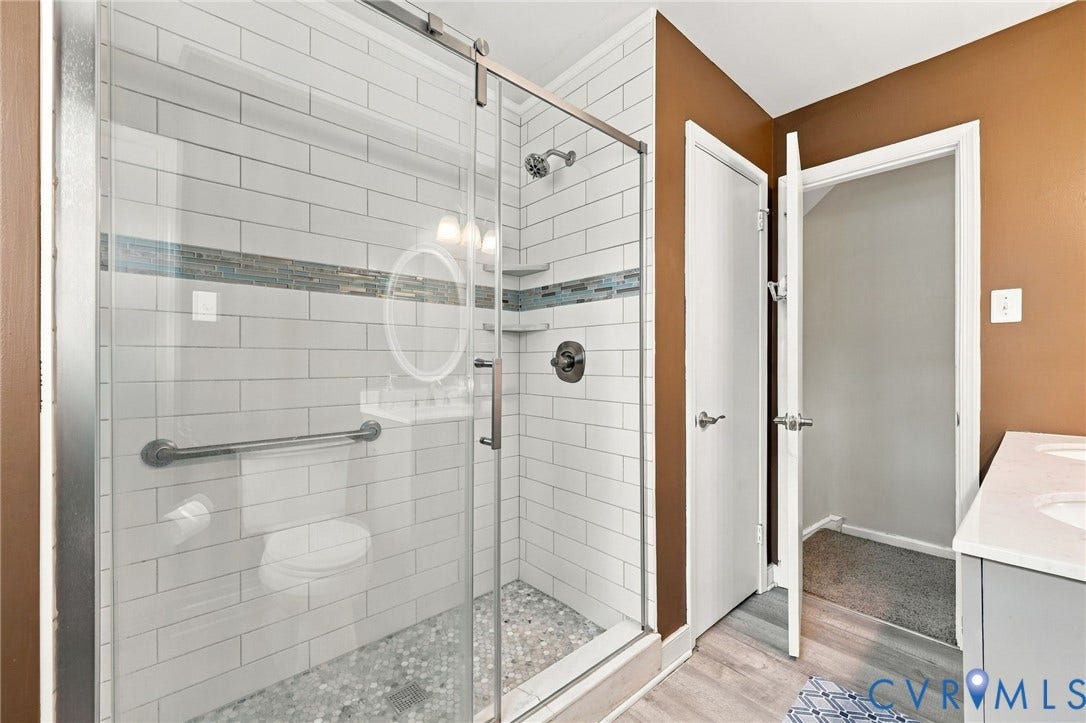 Glass-enclosed shower with subway tile surround, mosaic accent tile, and pebble-style floor