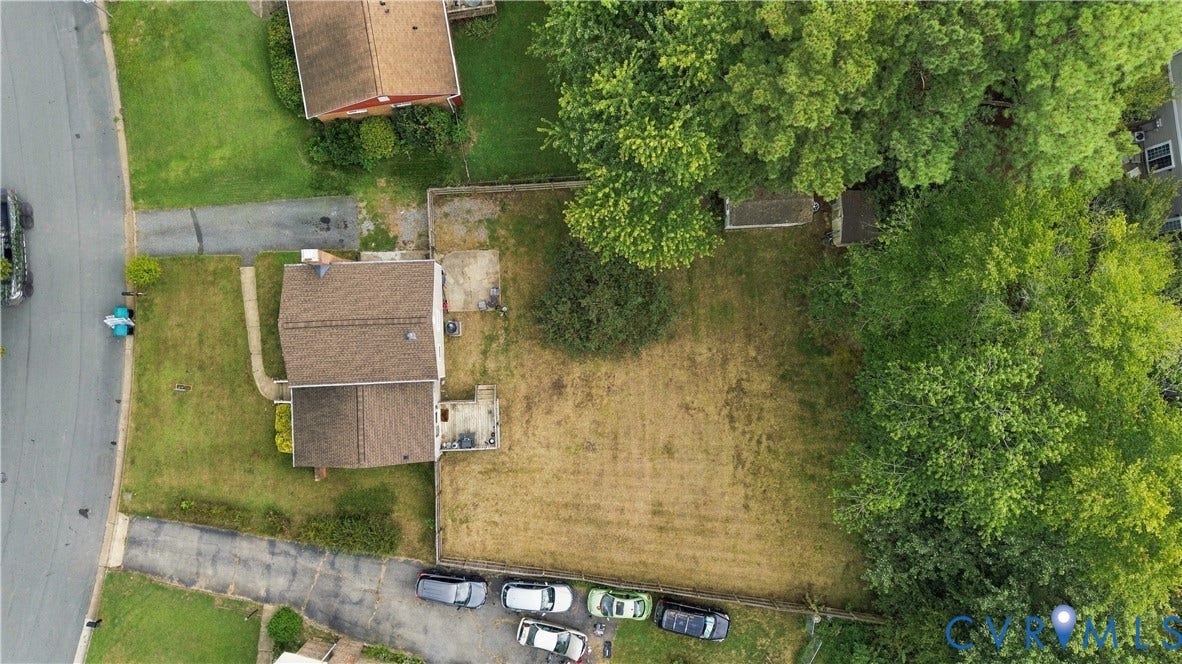 Expansive lot featuring mature perimeter trees, a detached shed, paved driveway, and established landscaping
