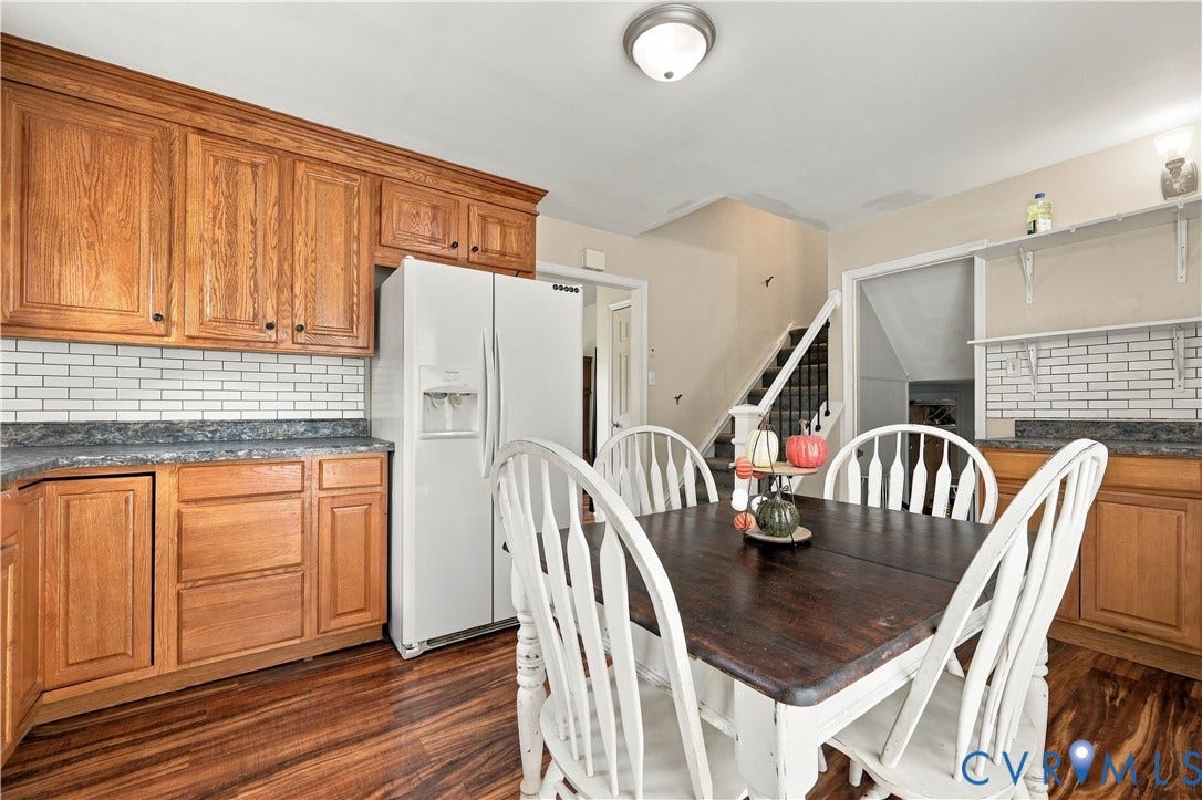 Wood-finish flooring, wood cabinetry, subway tile backsplash, and light-toned walls