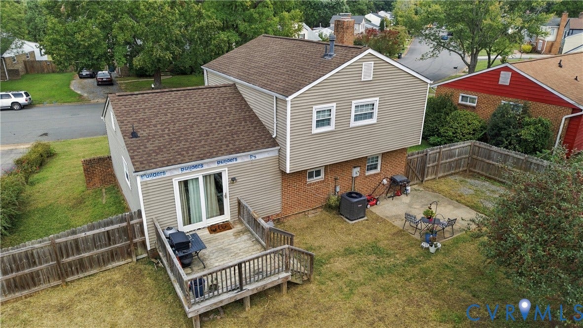 Two-story residence featuring a wood deck, sliding glass doors, and a fenced backyard