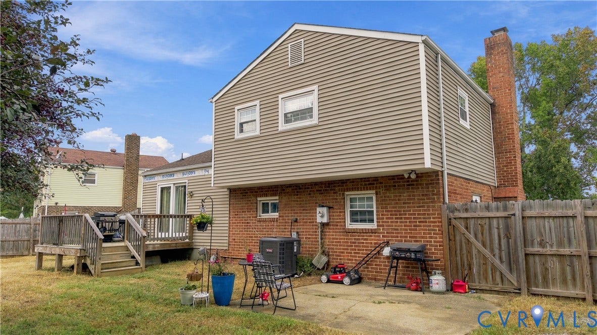 Rear exterior featuring brick and siding, a two-story wood deck, and a concrete patio