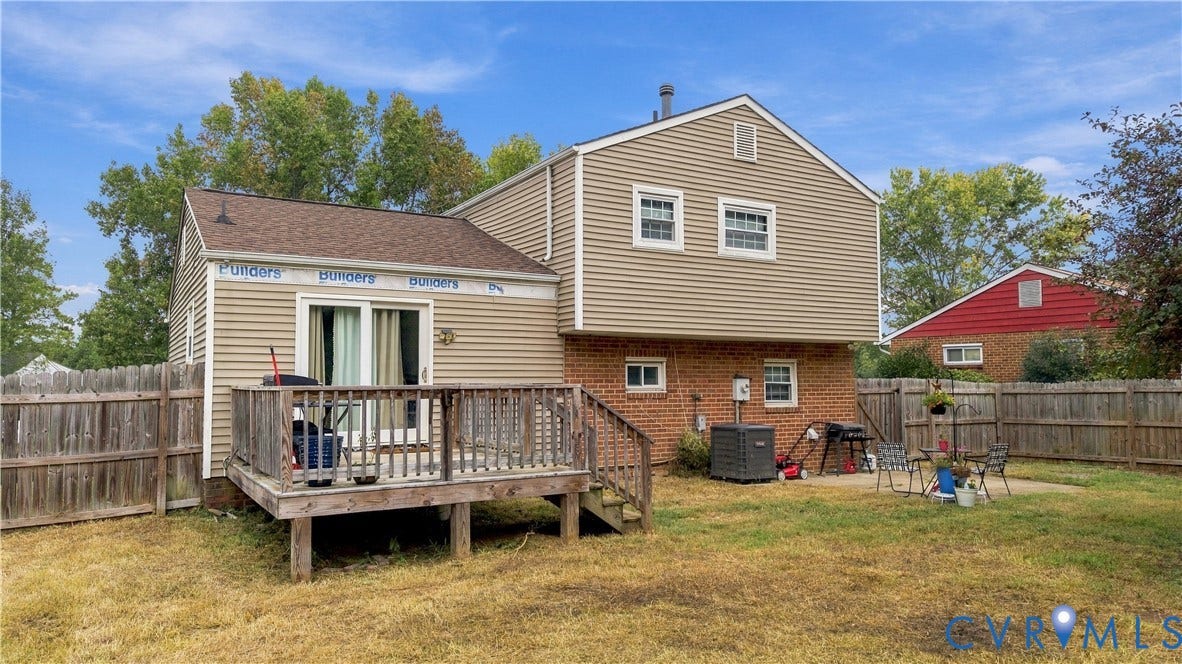 Rear exterior featuring a wood deck, sliding glass door, and fenced backyard