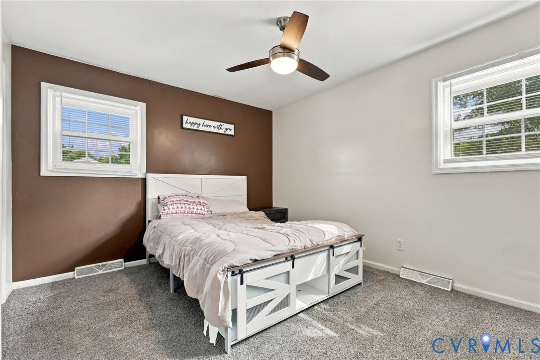 Room with dual windows, a ceiling fan with integrated lighting, and carpeted flooring