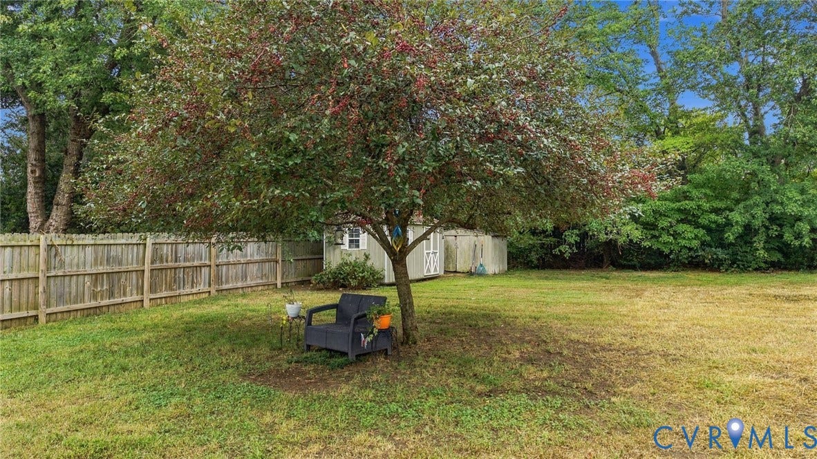 Expansive lawn with mature trees and a wooden privacy fence