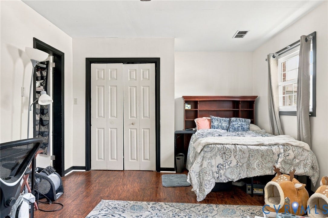 Wood-finish flooring throughout, white walls with dark trim, white bi-fold closet doors, and a window with natural light