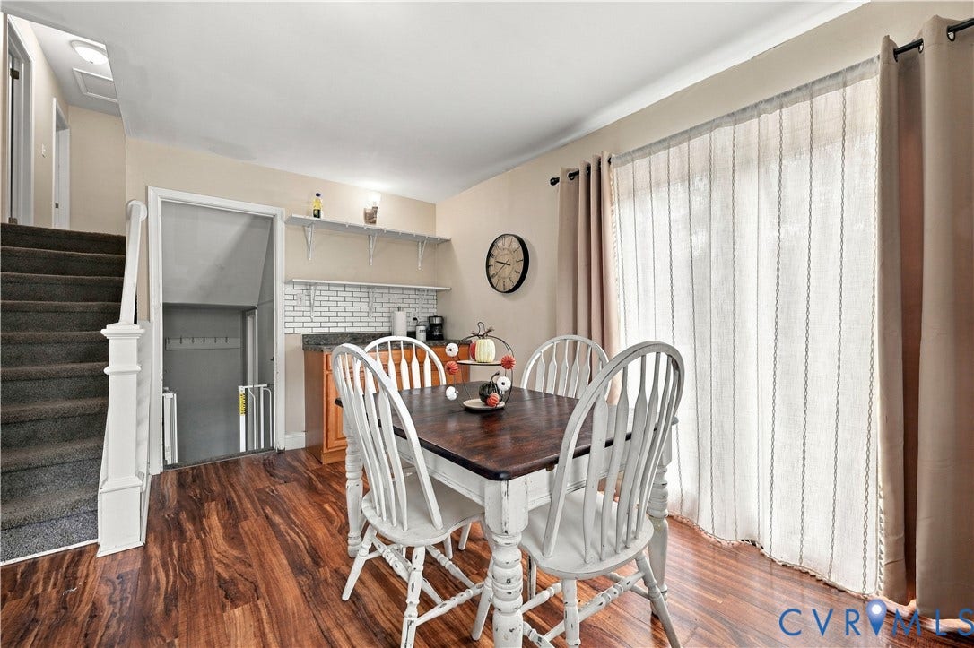 Wood-finish flooring, white subway tile backsplash, built-in shelving, and a sliding glass door