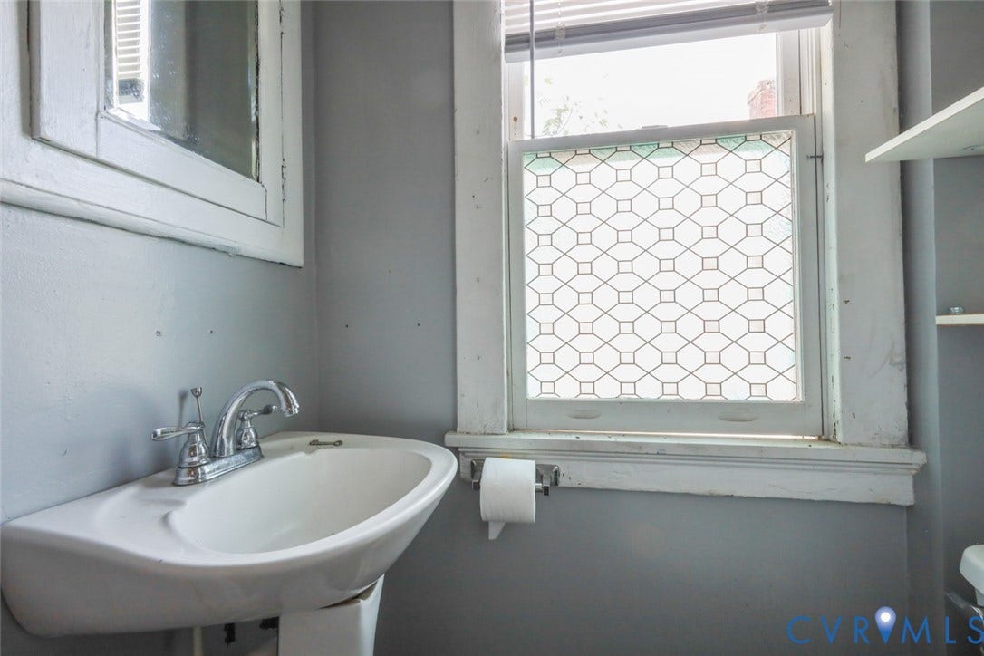 209 W 34th Street, Richmond, VA 23225 Pedestal sink with chrome faucet, complemented by a window featuring a decorative privacy film