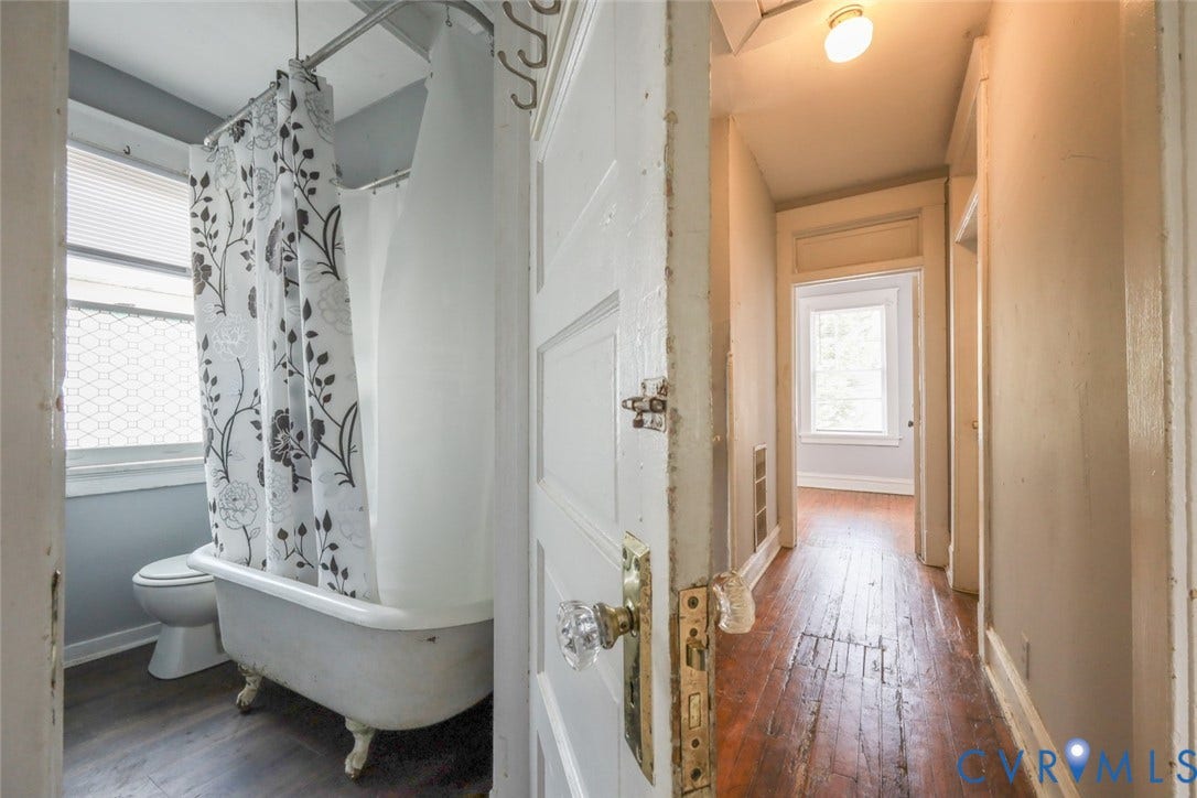 209 W 34th Street, Richmond, VA 23225 Bathroom featuring a clawfoot tub with shower conversion, window with blinds, and wood-finish flooring