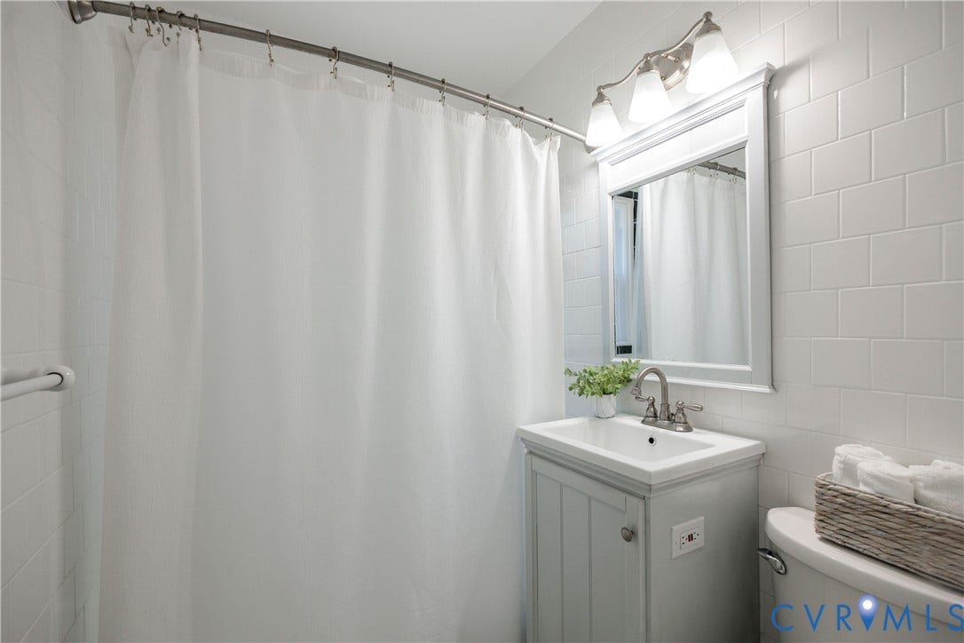 6710 Hanover Avenue, Westhampton Heights, Richmond, VA 23226 White subway tile surround, vanity with an integrated sink, framed mirror, and brushed nickel fixtures
