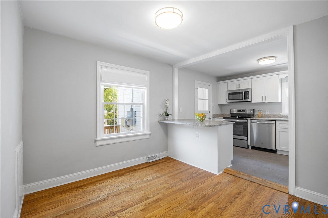 6710 Hanover Avenue, Westhampton Heights, Richmond, VA 23226 Hardwood flooring, window with white trim, white cabinetry, stainless steel appliances, and a quartz countertop breakfast bar and dining area