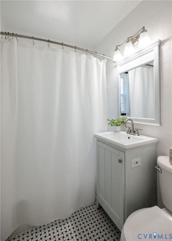 6710 Hanover Avenue, Westhampton Heights, Richmond, VA 23226 Bathroom featuring basketweave tile flooring, white subway tile walls, a single-sink vanity with a light gray cabinet, and a wall-mounted mirror with overhead lighting