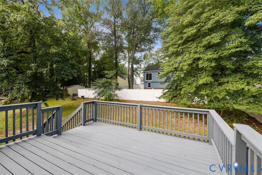 Expansive wood deck with painted railings, stairs, and a level backyard