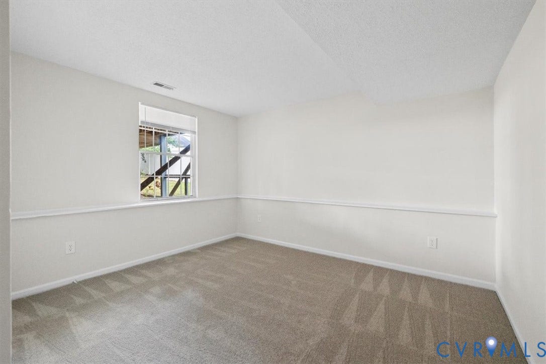 Carpeted flooring, white walls, picture rail molding, and a window providing natural illumination