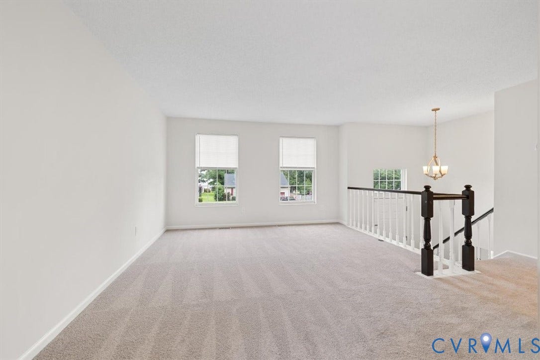 Neutral tone wall finishes, carpeting, multiple windows, and a chandelier lighting fixture in foyer