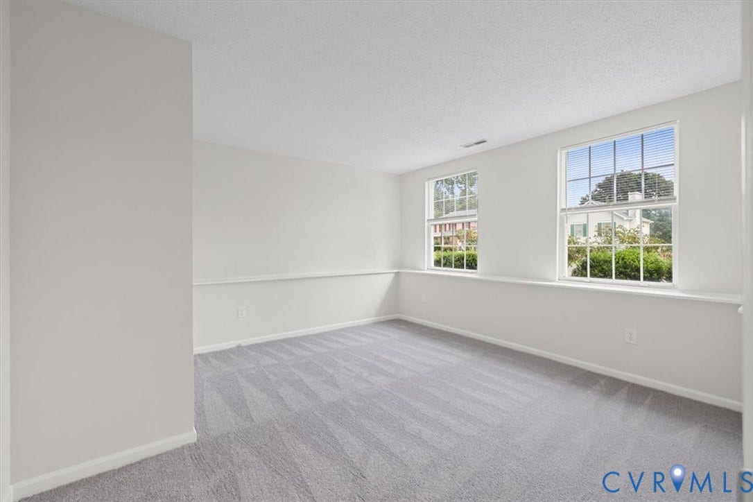 Light gray carpeting, white walls, two double-hung windows, and white trim