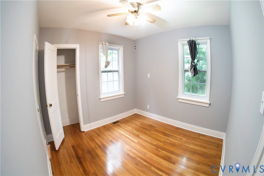 6706 Jahnke Road, Richmond, VA 23225 Hardwood flooring, light gray wall finish, two windows with white trim, built-in closet with shelving, and a ceiling fan