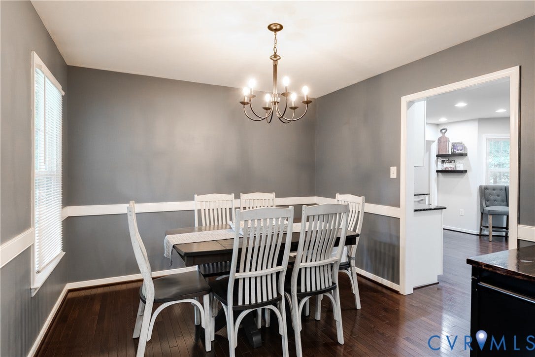 2844 Broadford Lane, Henrico, VA 23233 Elegant dining room featuring warm wood-finish flooring, a black dining table with white spindle-back chairs, and soft natural light from dual windows