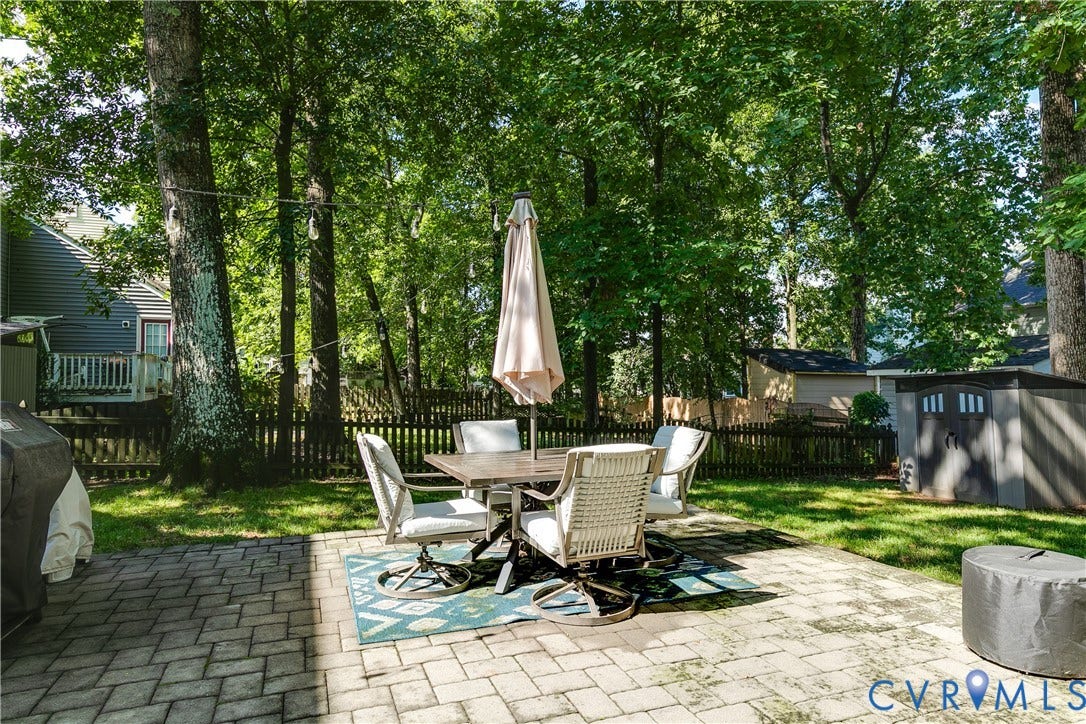 2844 Broadford Lane, Henrico, VA 23233 Paver patio with a lush lawn, mature trees, wood fence, and a storage shed