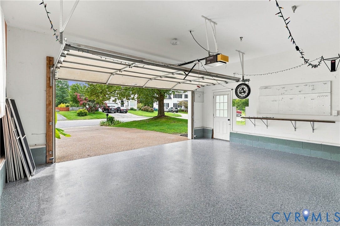 Garage with a speckled epoxy floor, white walls, and a built-in wall shelf