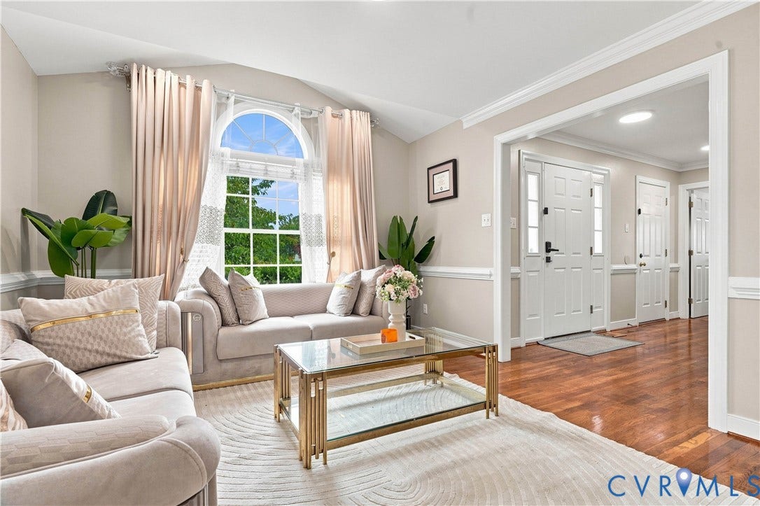Vaulted ceiling with an arched window, wood flooring, and crown molding