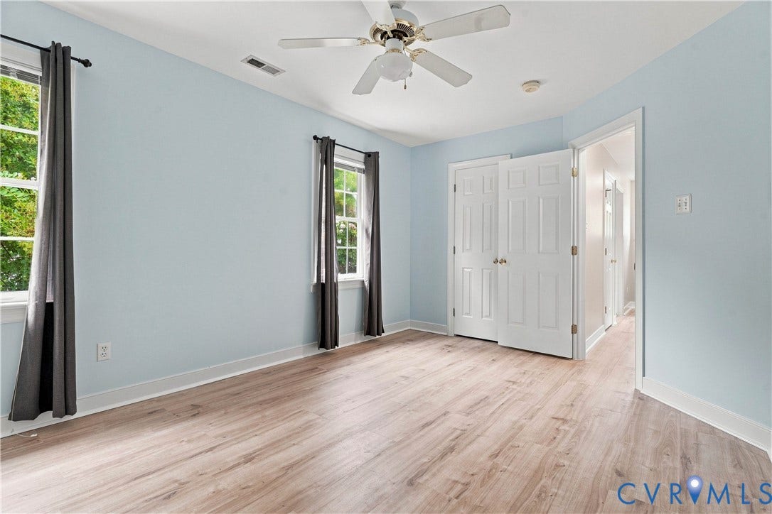 Light wood-finish flooring, two windows, ceiling fan, and bi-fold closet doors