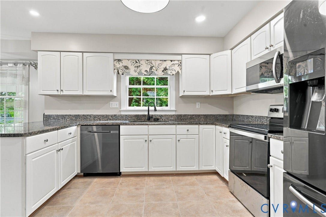 White cabinetry with dark hardware, granite countertops, tile flooring, and stainless steel appliances