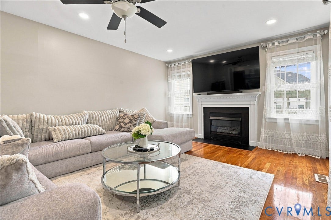 Recessed lighting, ceiling fan, wood-finish flooring, fireplace with white mantel, and multiple windows