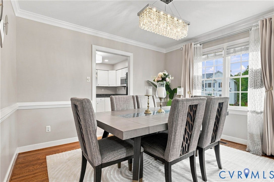 Hardwood-finish flooring with an area rug, crown molding, a crystal chandelier, and large windows