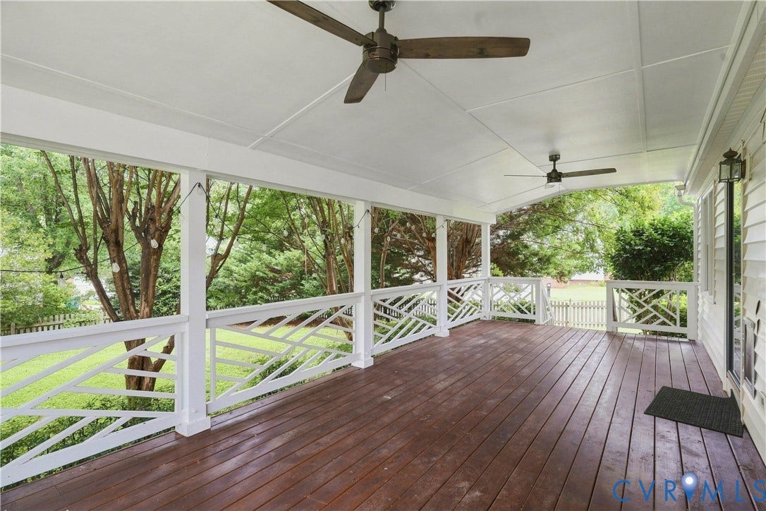 Spacious covered porch with dark wood-finish flooring, white railing, and dual ceiling fans