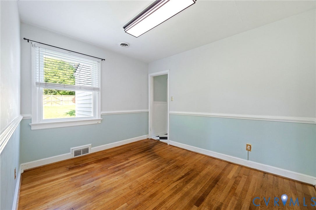 808 W 47th Street, Richmond, VA 23225 Hardwood flooring, painted walls with chair rail molding, a single window with blinds, and an overhead fluorescent light fixture