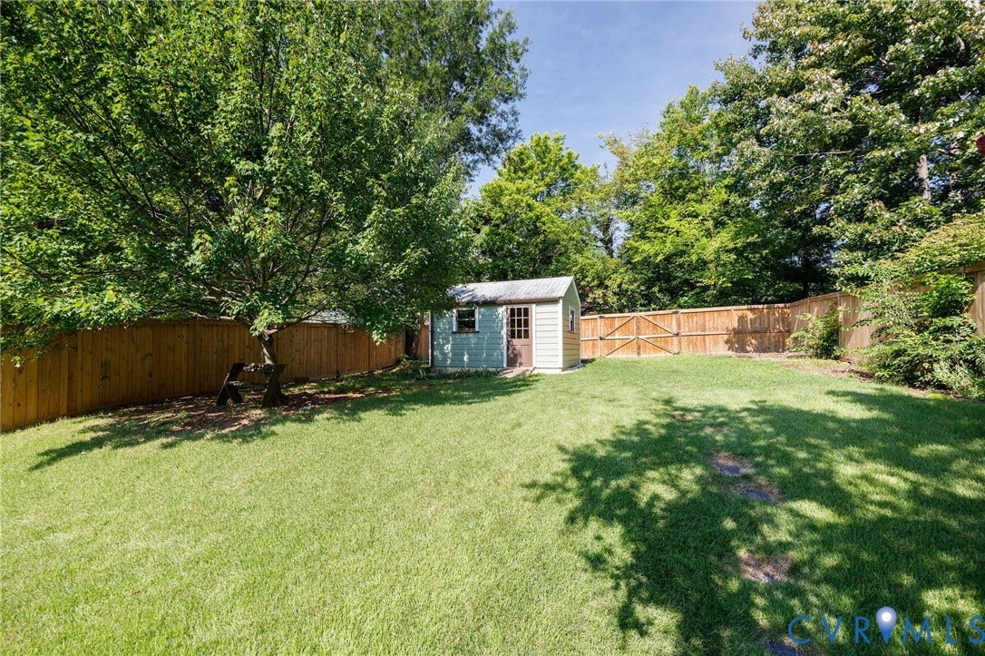 808 W 47th Street, Richmond, VA 23225 Expansive backyard featuring a lush lawn, mature trees, wood privacy fencing, and a detached storage shed